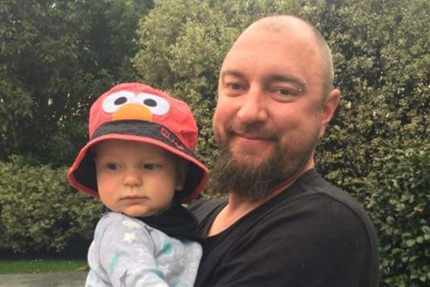 A man holding a toddler in a garden