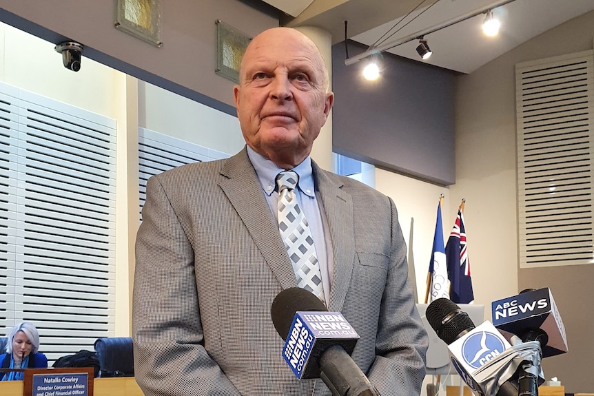 Man stands behind microphones for press conference inside