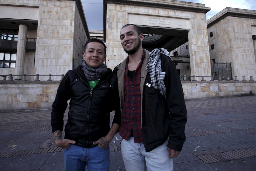 Two men pose in front of the Justice Palace in Bogota.