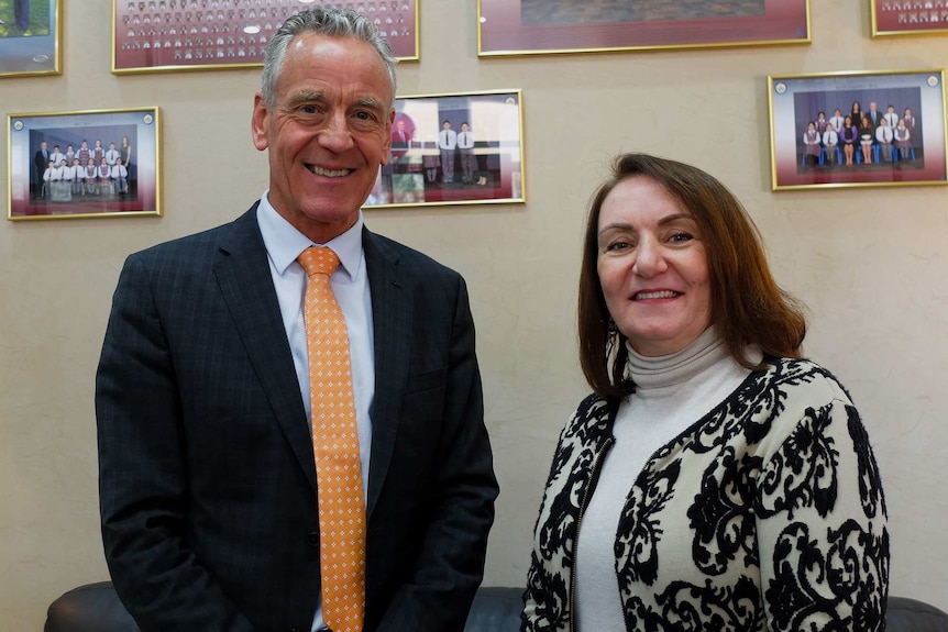 St Hurmizd head principal Brian Kennelly and Christian studies coordinator Rowena Daniel standing in front of school photographs