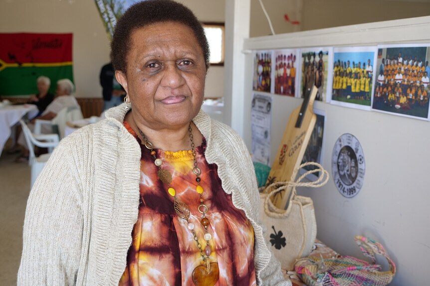 Aunty Roz Wallace stands in a room with Vanuatu themed props beside her.