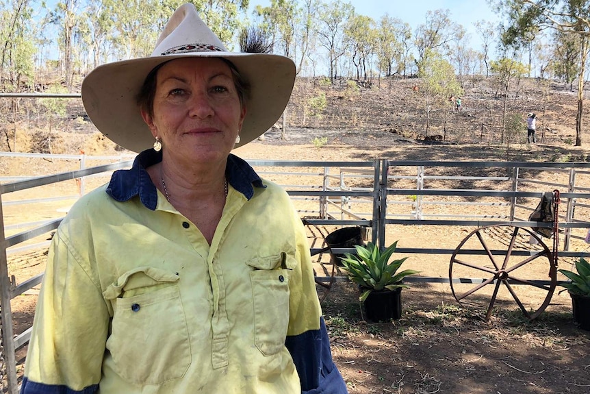 Gracemere resident Grace Cairns stands near a cattle yard with burnt bushland behind her on her property.