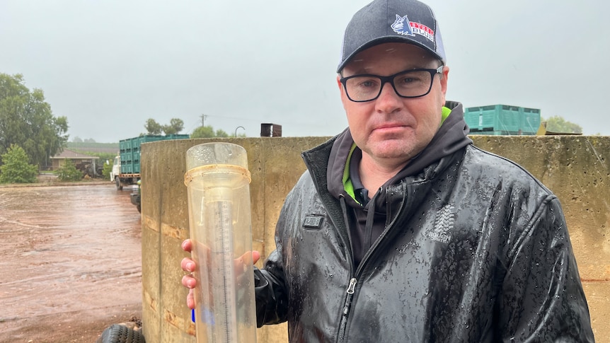 A man standing outside in the rain with a rain gauge