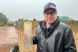 A man standing outside in the rain with a rain gauge