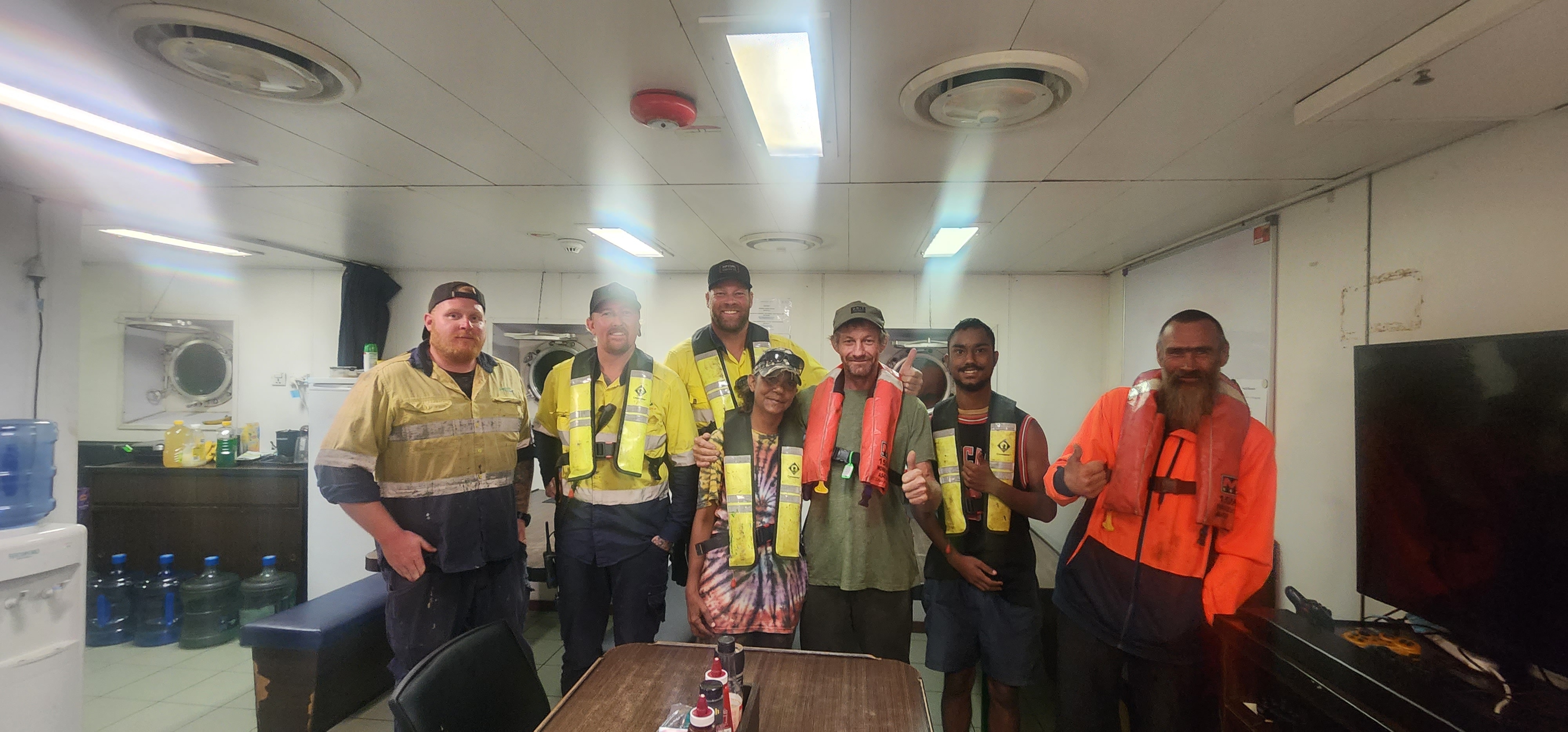A group of men in hi-visibility vests inside a ship