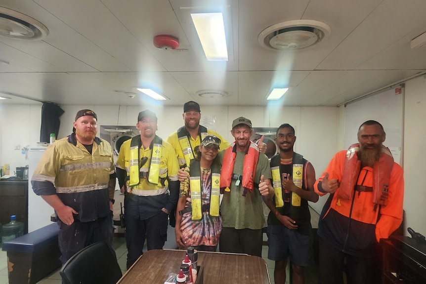 A group of men in hi-visibility vests inside a ship