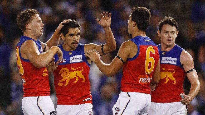 A group of Brisbane Lions players congratulate Charlie Cameron (second left) after a goal.