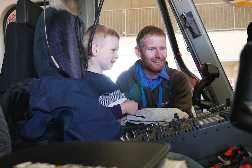 A father shows his son the cockpit of a helicopter