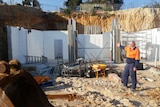 Lee Richardson stands in front of construction site of his new house
