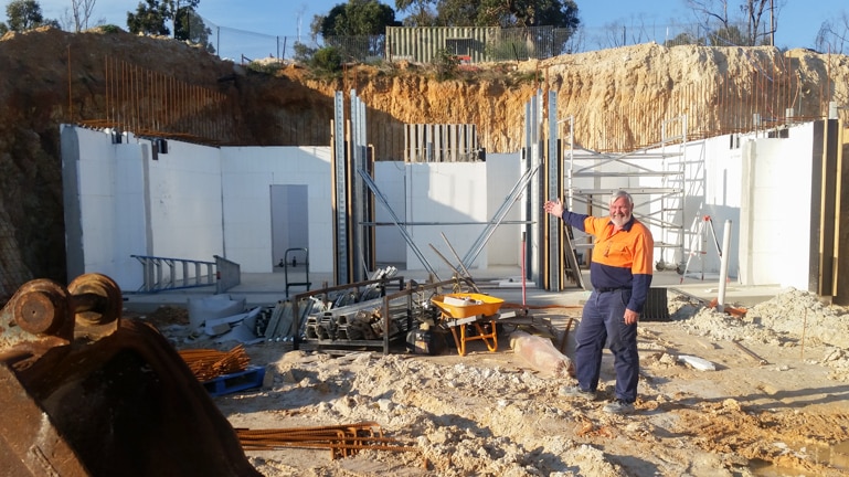 Lee Richardson stands in front of construction site of his new house