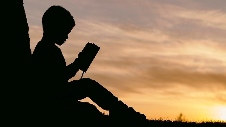 Silhouette of child reading a book
