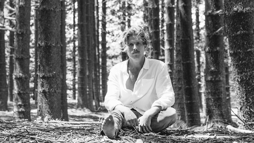 Black and white image of Ziggy Alberts sitting in a forest