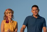A still from the movie Fly Me to the Moon with Scarlett Johansson and Channing Tatum in 50s clothes standing on a wooden bridge