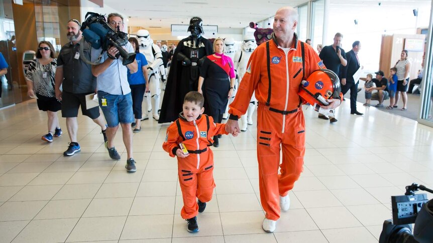 Dwayne and an astronaut in their space suits walking through Adelaide Airport.