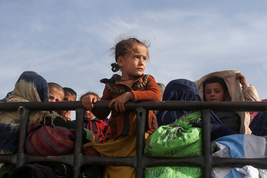 A child rests their arm on a handrail on a truck.