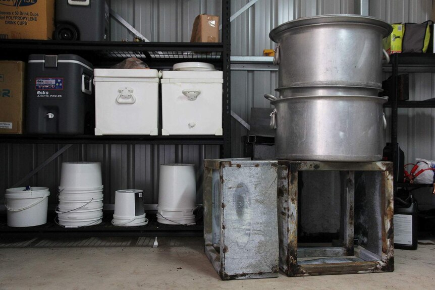 A shed filled with several large vats, an esky, and some containers.