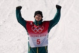 Australian Winter Olympics bronze medallist Tess Coady smiles and raises her arm in triumph after her event in Beijing.