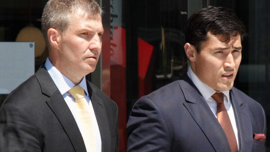 Two men leave the ACT Magistrates Court wearing suits and ties.