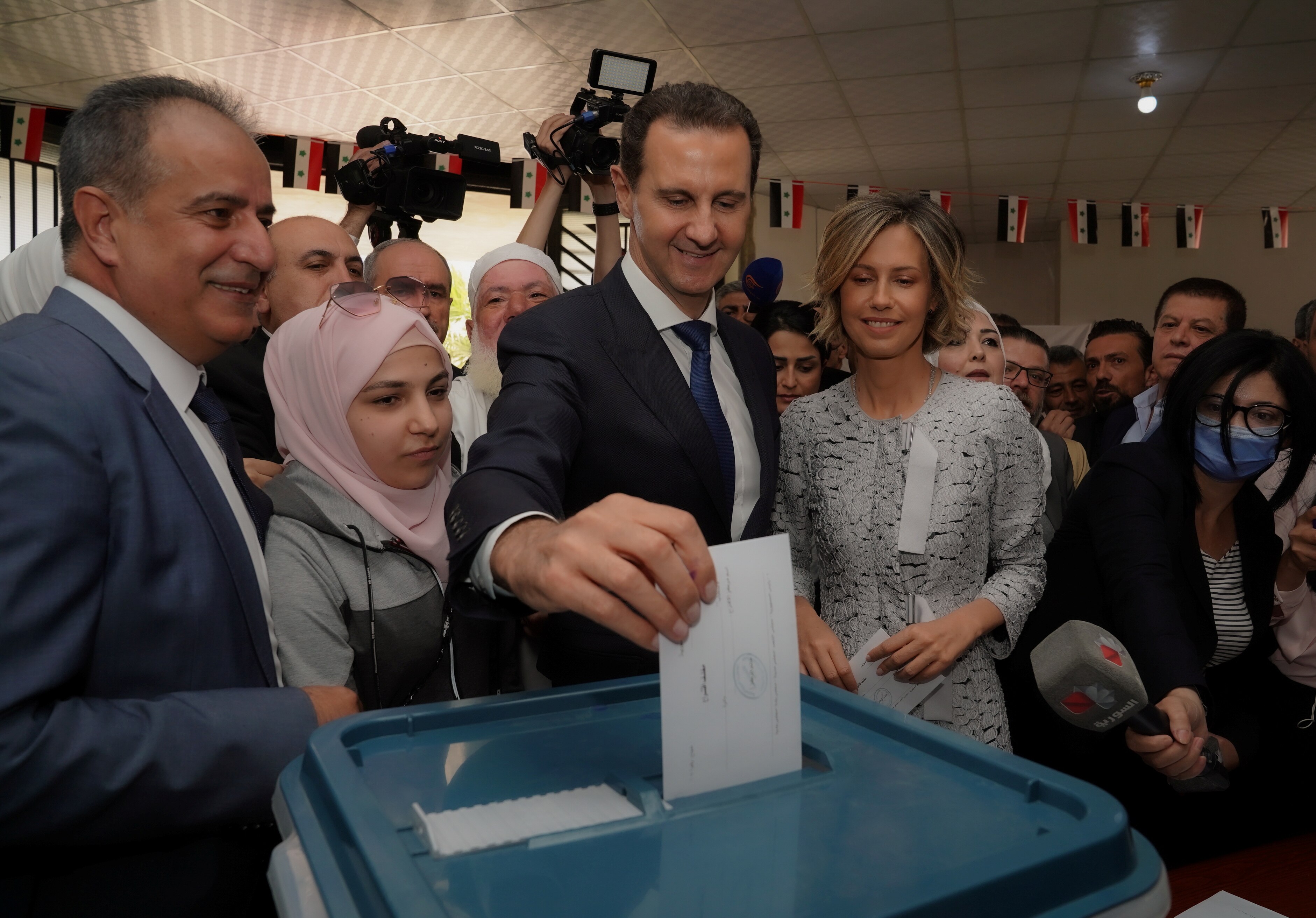 Bashar al-Assad puts a ballot in a box. 