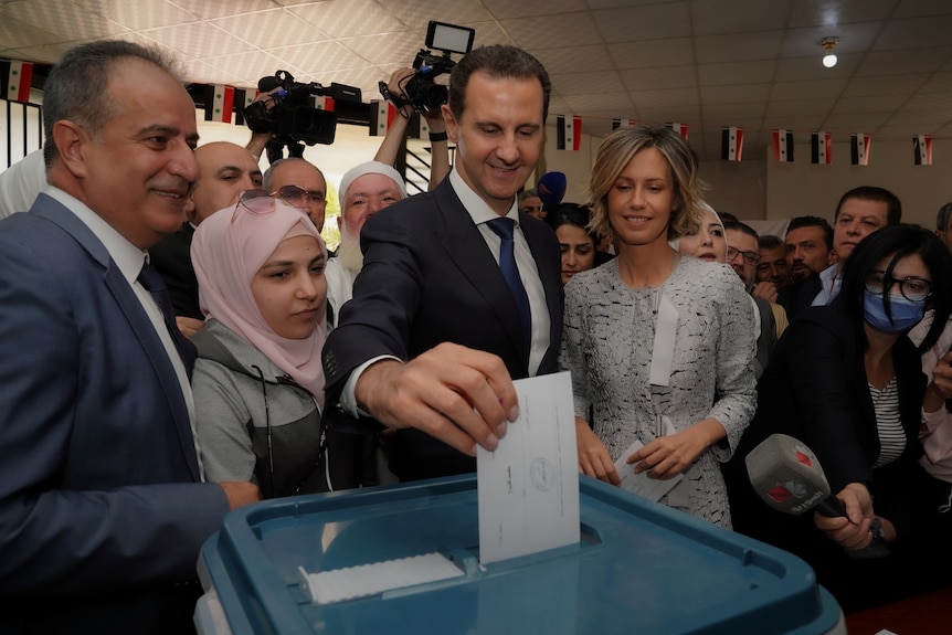 Bashar al-Assad puts a ballot in a box. 