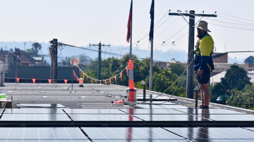 Worker installs solar panels on a flat roof