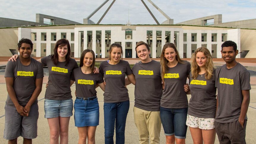 Group of young people wearing Heywire t-shirts stand outside Parliament House