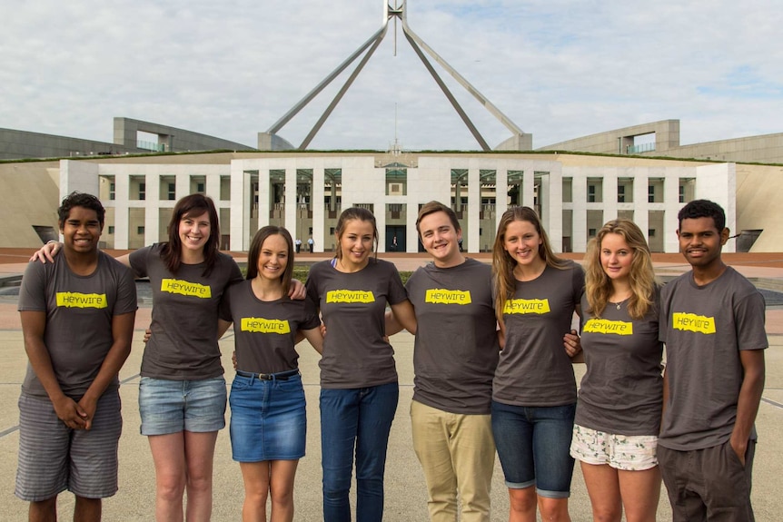 Group of young people wearing Heywire t-shirts stand outside Parliament House