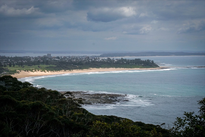 A picture of the bay with a small village of homes on a headland overlooking the water.