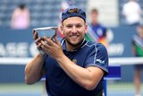 Australian wheelchair tennis star Dylan Alcott wears a beaming smile as he holds the US Open trophy in his hands.