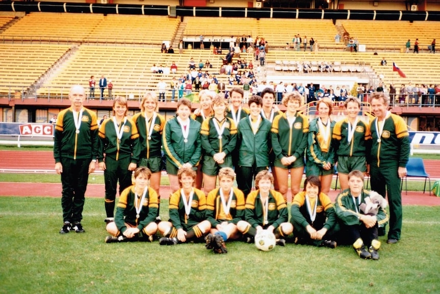 A soccer team wearing green and yellow tracksuits poses for a photo