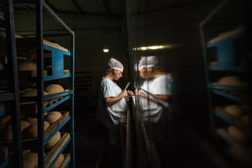 A woman standing between rows of bread