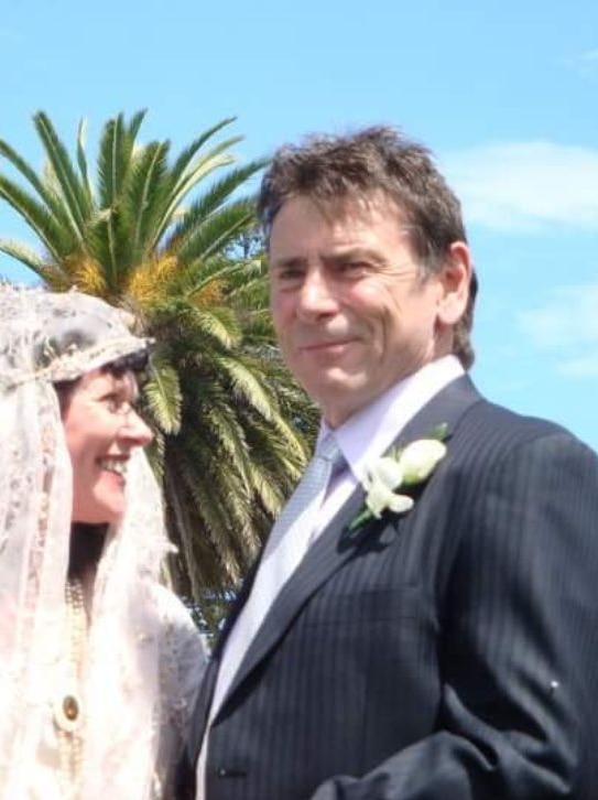 A middle aged man outside in suit at a wedding