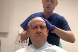 A man's head is shaved in preparation for surgery.