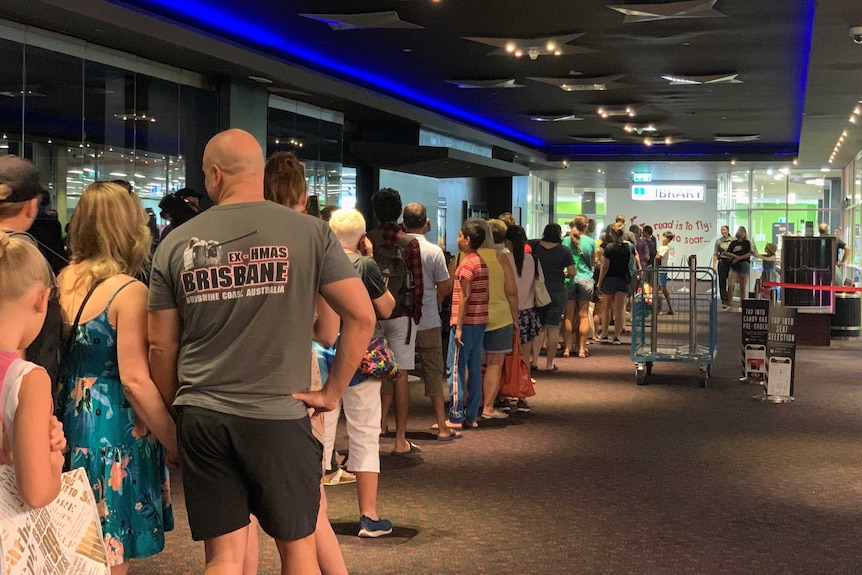 Dozens of people stand outside a library waiting to get inside