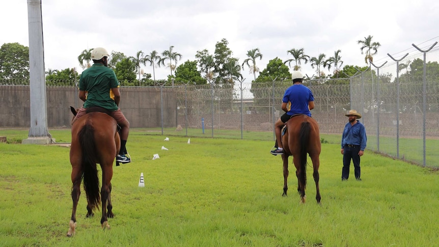 Two young people ride horses as Marc Gallagher instructs them at Darwin's Don Dale youth detention centre.