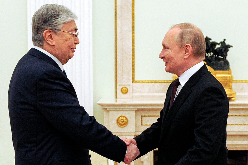 Russian President Vladimir Putin greets Kazakhstan's President Kassym-Jomart Tokayev with a handshake.
