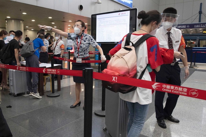 Airport staff redirect a traveller at a checkpoint for people from high risk areas to present test results before checking in