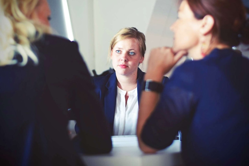 Woman speaking to two other women at business meeting for a story about what to do before buying a home with your partner.