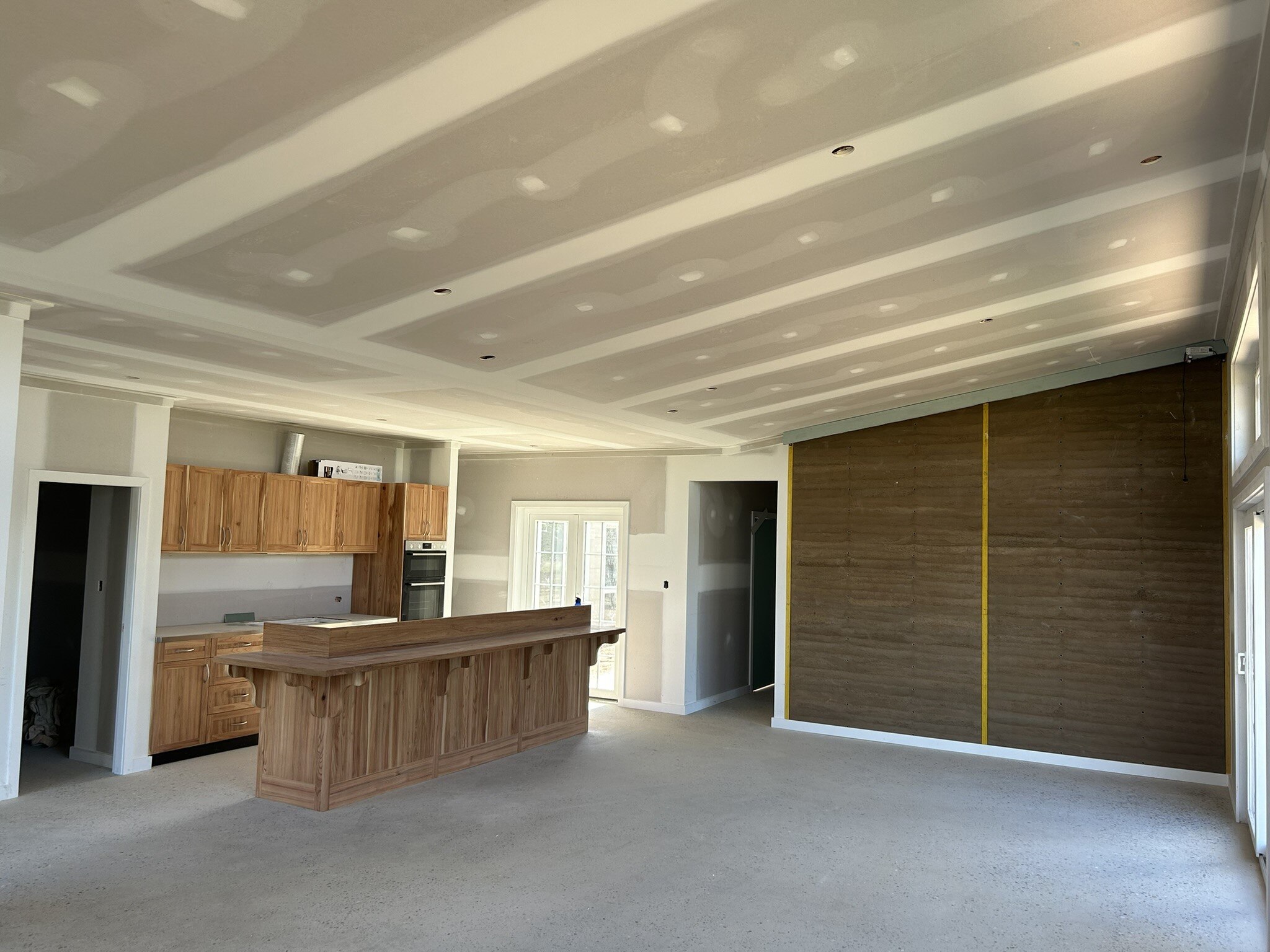 A wide shot of a kitchen with timber features included in a milled timber wall. The room is still under construction.