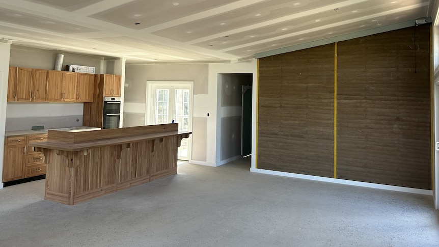 A wide shot of a kitchen with timber features included in a milled timber wall. The room is still under construction.