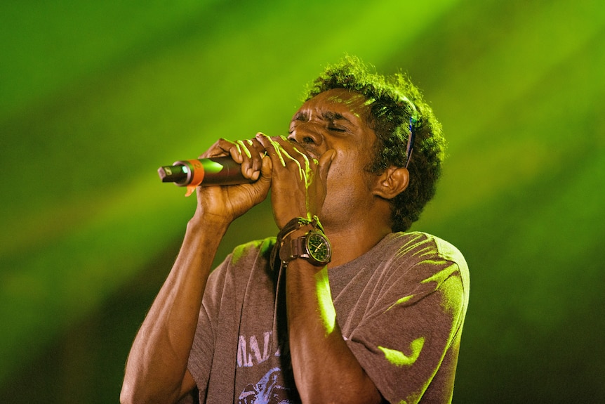 an aboriginal man singing passionately on stage