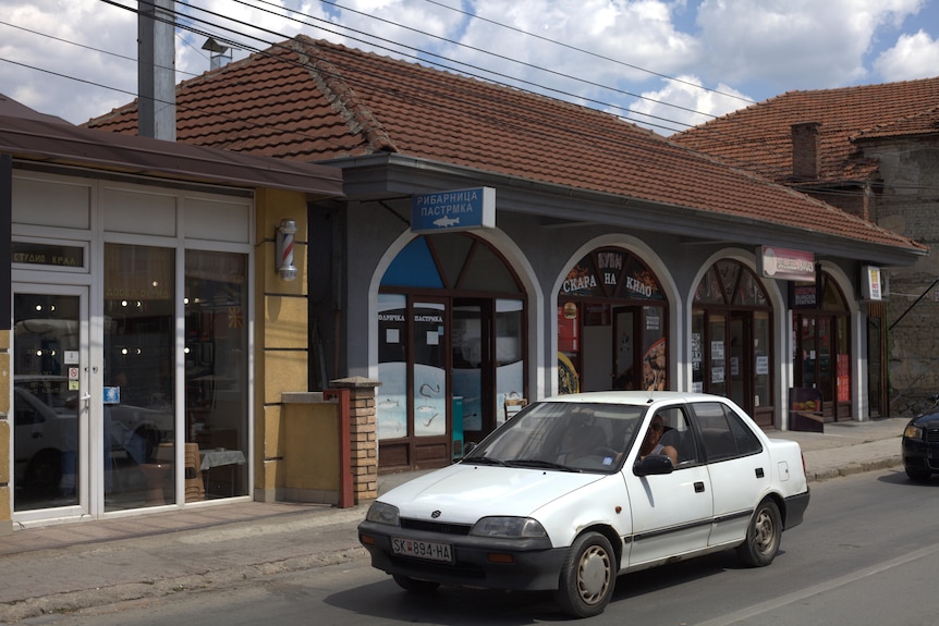 An old white car outside a business