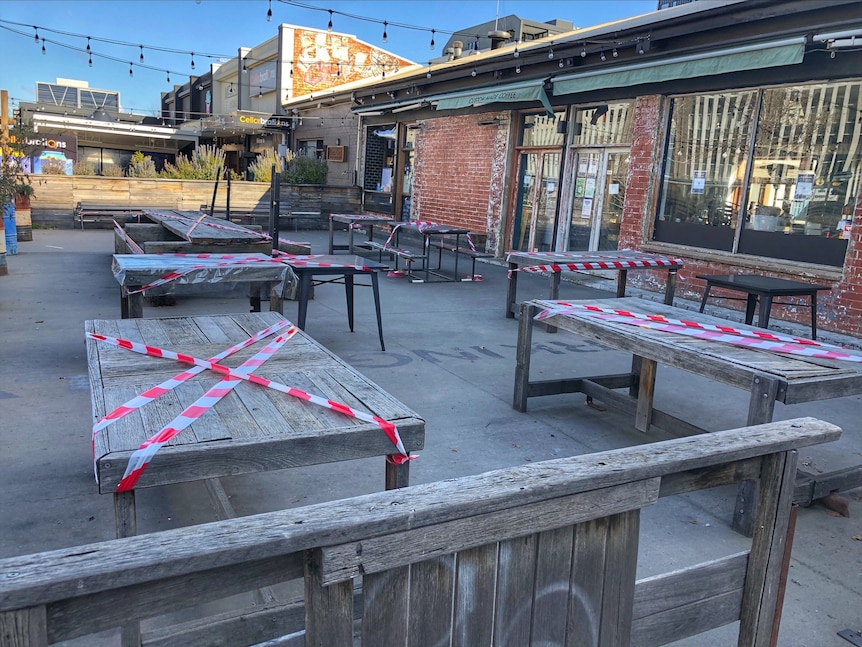 Tables have strips of tape across them to stop people from gathering in the outside area of the cafe.