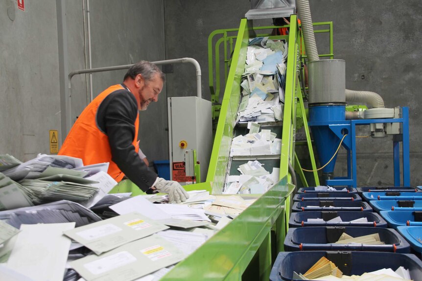 Michael Mischin sorts through letters as they fall down a conveyer belt.