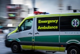 A green and yellow ambulance driving on a road