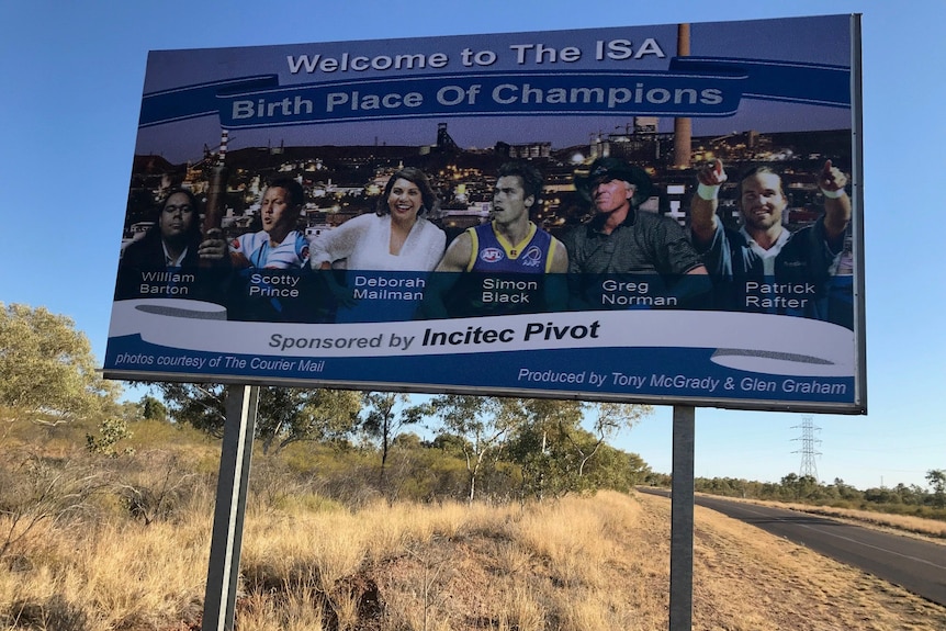 A road sign says "Welcome to the Isa: Birthplace of champions" with pictures of famous men and women