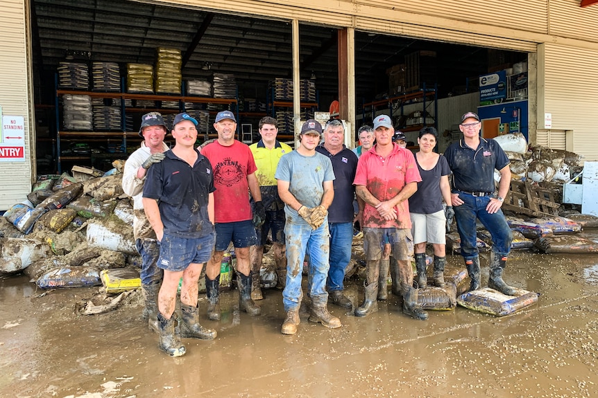 A dozen people wearing gumboots standing in front of damaged feed bags.