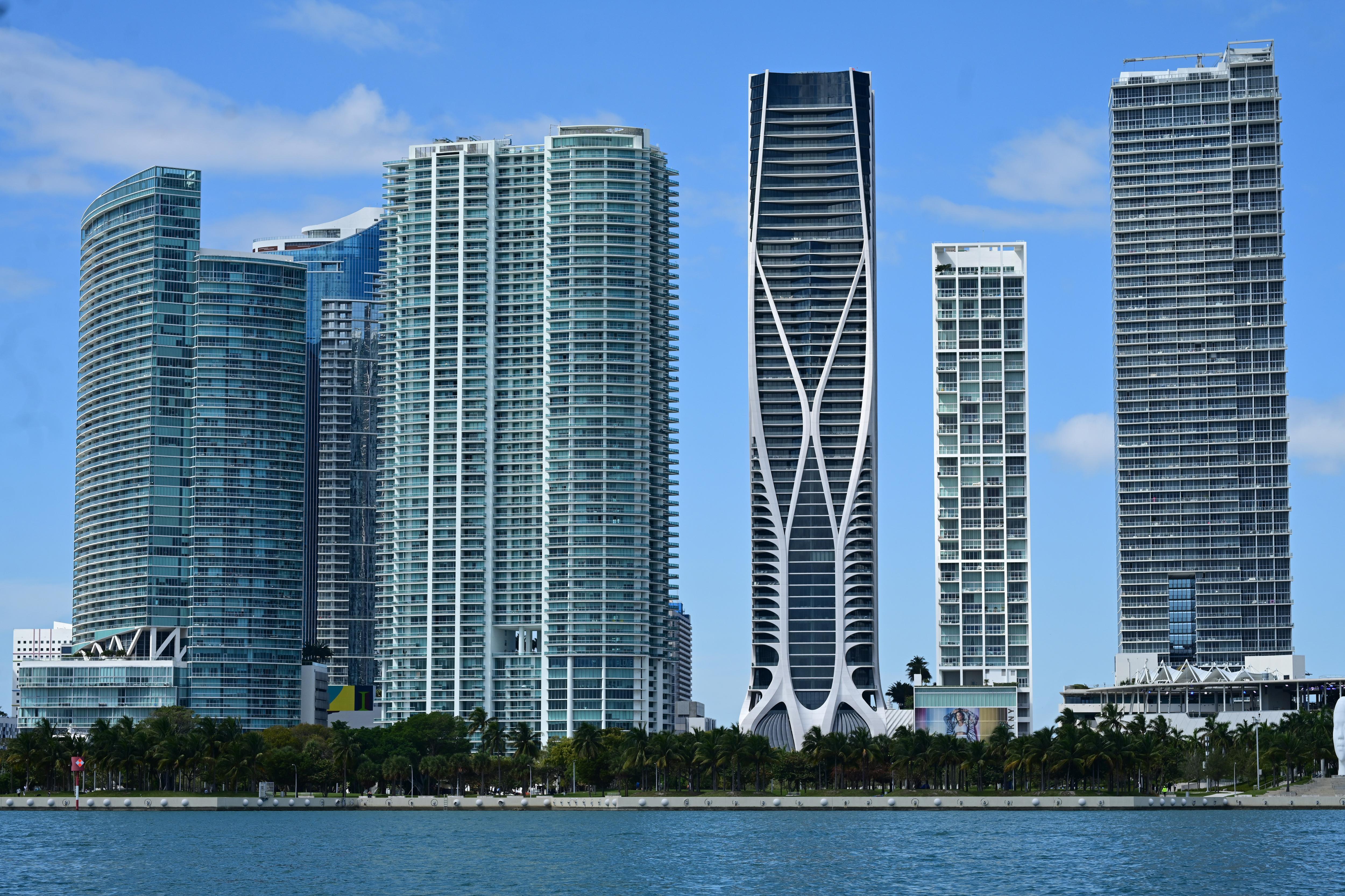 A photo of sky scrapers with blue skies in front of a beach in Miami.