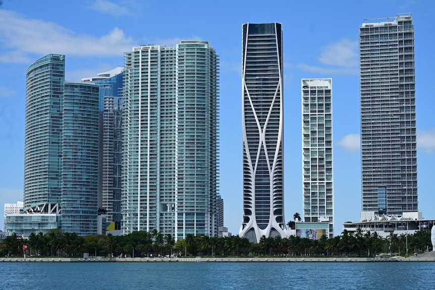 A photo of sky scrapers with blue skies in front of a beach in Miami.