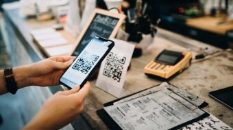 A person holds out a phone to scan a QR code at a counter.